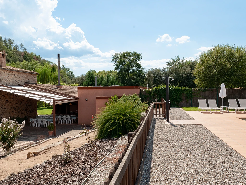 Zona de barbacoa a l'esquerra, a la dreta més elevada, la piscina